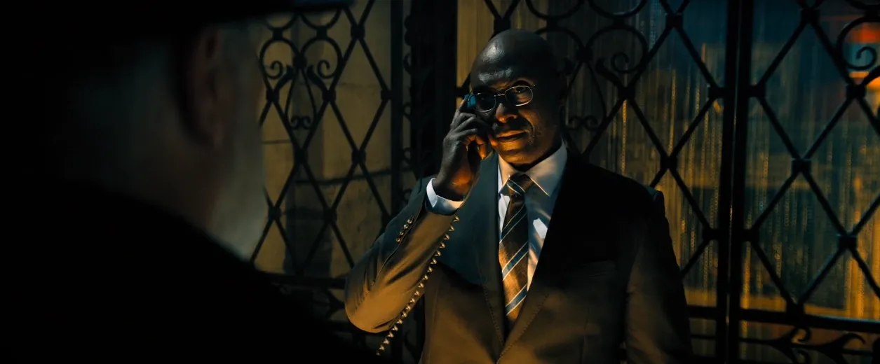 Charon from John Wick standing at the hotel front desk